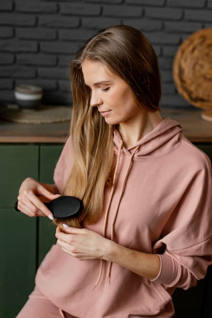 Mujer sonriente de tiro medio cepillarse el cabello