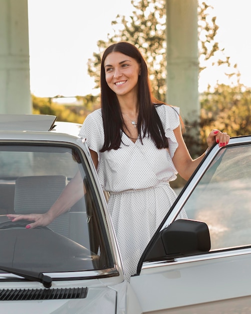 Mujer sonriente de tiro medio cerca del coche