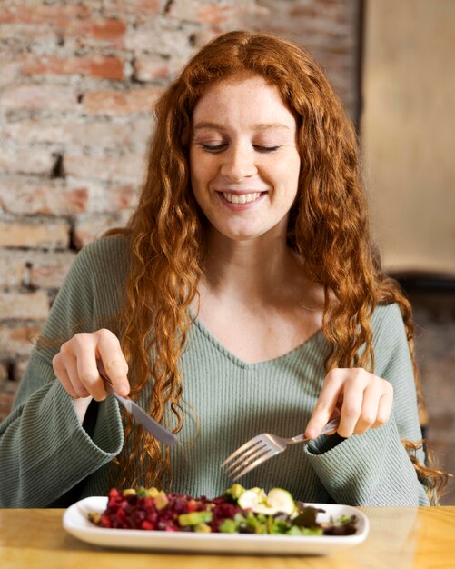 Mujer sonriente de tiro medio comiendo