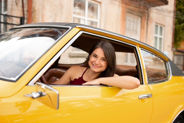 Mujer sonriente de tiro medio conduciendo coche