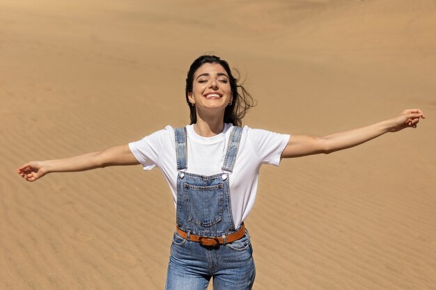 Mujer sonriente de tiro medio en el desierto