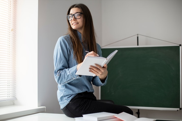 Mujer sonriente de tiro medio escribiendo en cuaderno