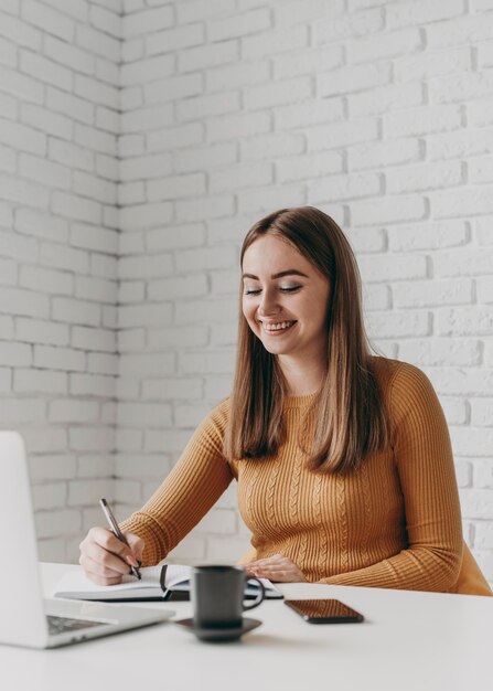 Mujer sonriente de tiro medio escribiendo