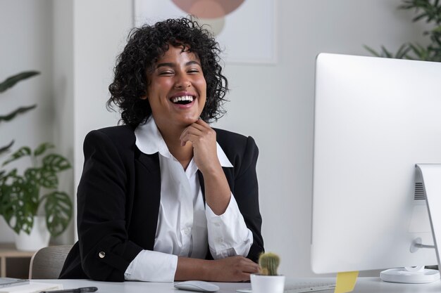 Mujer sonriente de tiro medio en el escritorio