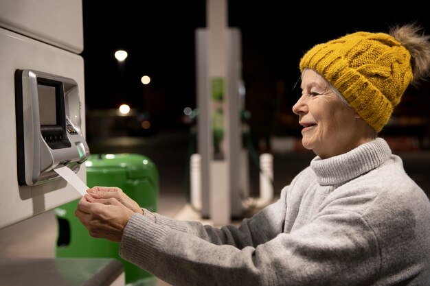 Mujer sonriente de tiro medio en la gasolinera