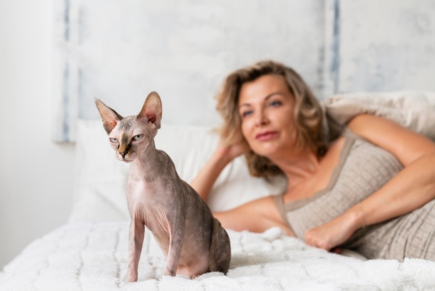 Mujer sonriente de tiro medio y gato en la cama