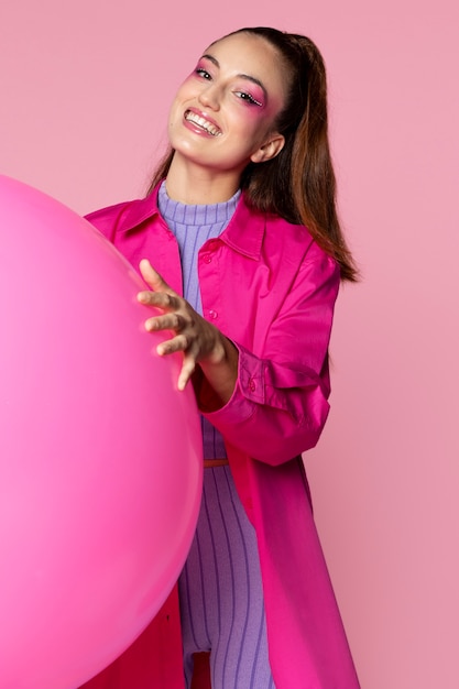 Mujer sonriente con tiro medio globo rosa