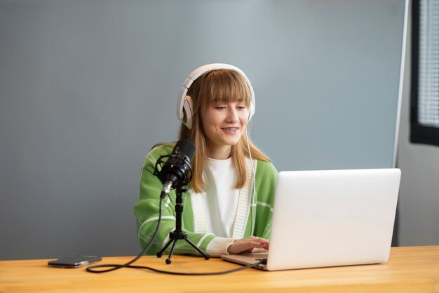 Mujer sonriente de tiro medio grabando podcast