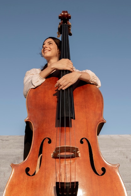 Mujer sonriente de tiro medio con instrumento