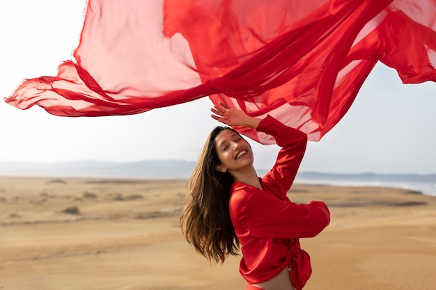 Mujer sonriente de tiro medio lanzando bufanda roja