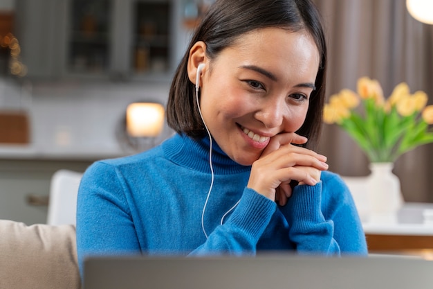 Foto gratuita mujer sonriente de tiro medio con laptop en casa