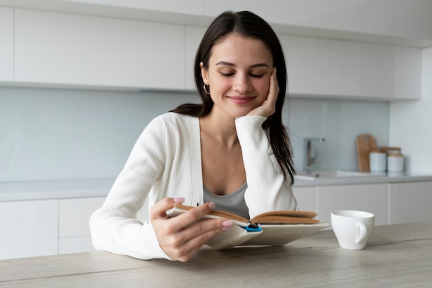 Mujer sonriente de tiro medio leyendo en casa