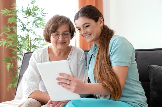 Mujer sonriente de tiro medio mirando tablet