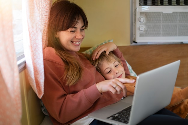 Mujer sonriente de tiro medio y niño con computadora portátil