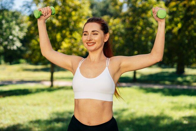 Mujer sonriente de tiro medio con pesas