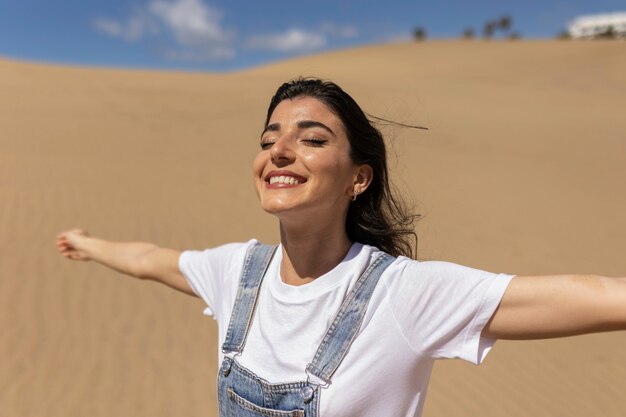 Mujer sonriente de tiro medio posando en el desierto