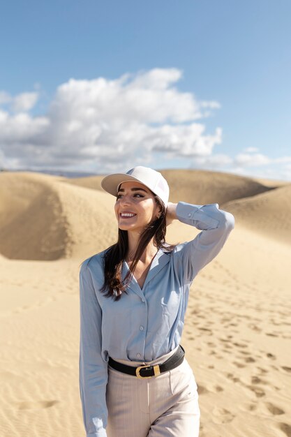 Mujer sonriente de tiro medio posando en el desierto