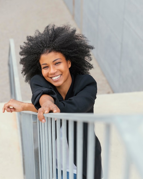 Mujer sonriente de tiro medio posando en las escaleras