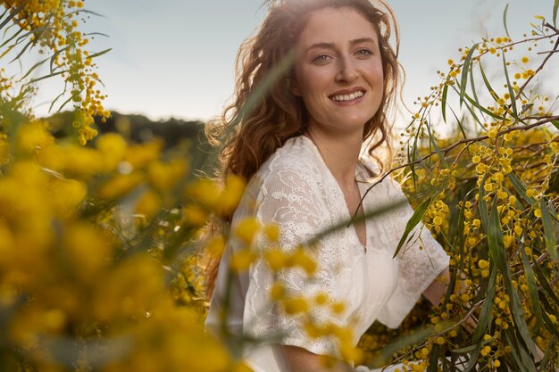 Mujer sonriente de tiro medio posando con flor de estepa