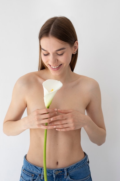 Mujer sonriente de tiro medio posando con flor