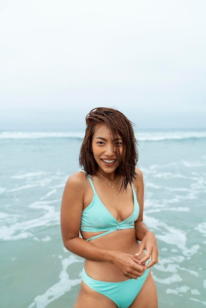Mujer sonriente de tiro medio posando en la playa