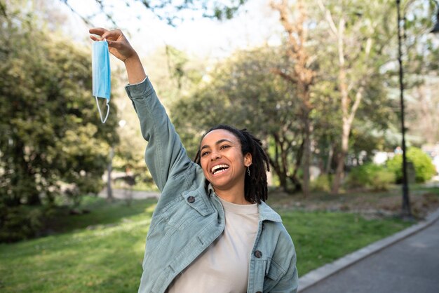 Mujer sonriente de tiro medio quitándose la máscara