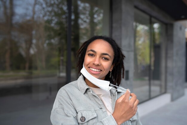 Mujer sonriente de tiro medio quitándose la mascarilla