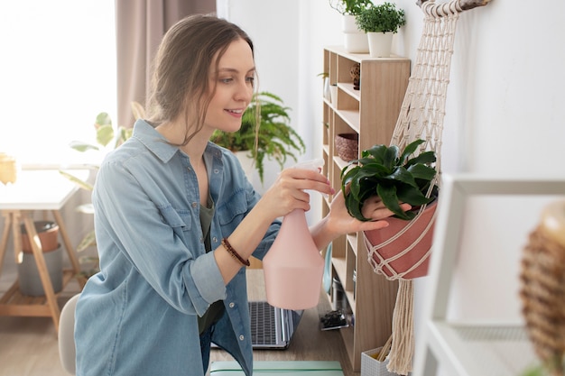 Mujer sonriente de tiro medio regando plantas