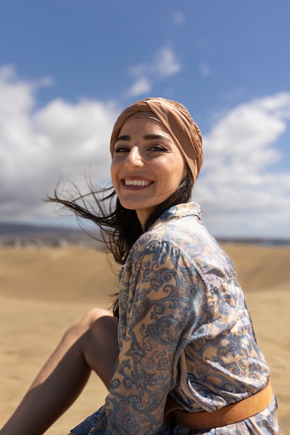 Mujer sonriente de tiro medio sentada en la arena