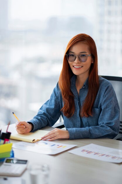 Mujer sonriente de tiro medio sentada en el escritorio