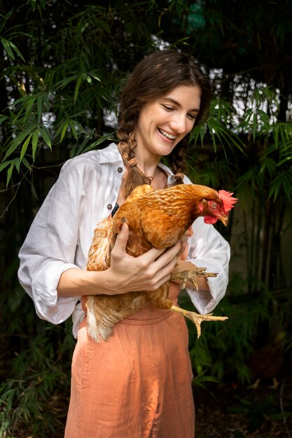 Mujer sonriente de tiro medio sosteniendo gallina