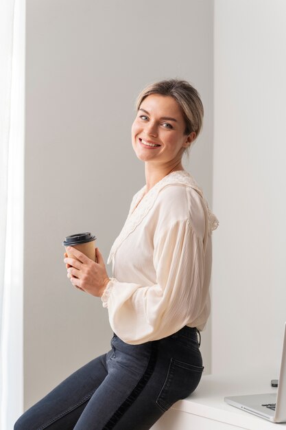 Mujer sonriente de tiro medio sosteniendo taza