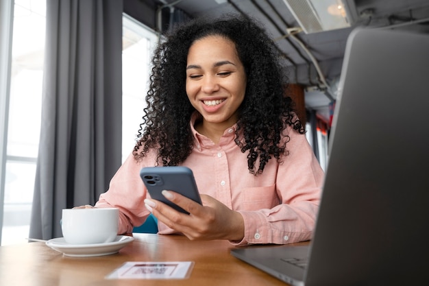 Mujer sonriente de tiro medio sosteniendo teléfono