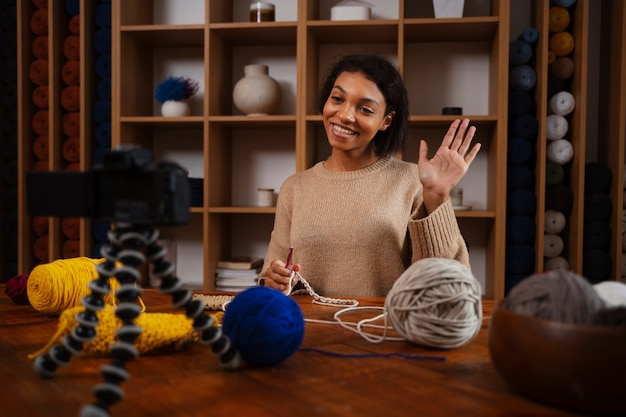 Foto gratuita mujer sonriente de tiro medio tejiendo en cámara