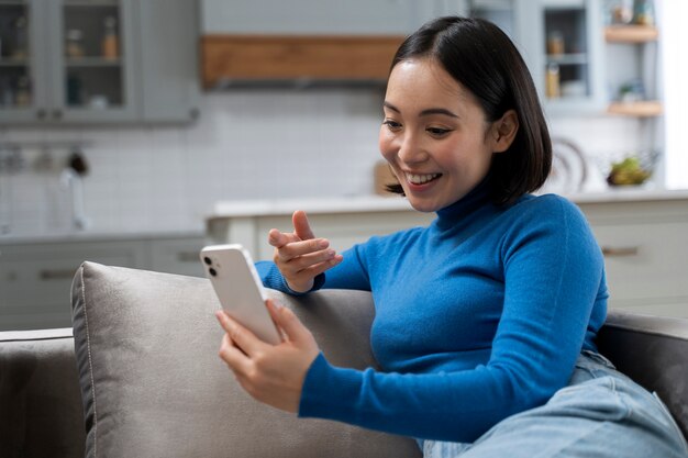 Mujer sonriente de tiro medio con teléfono inteligente