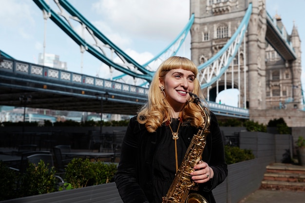 Mujer sonriente de tiro medio tocando el saxofón