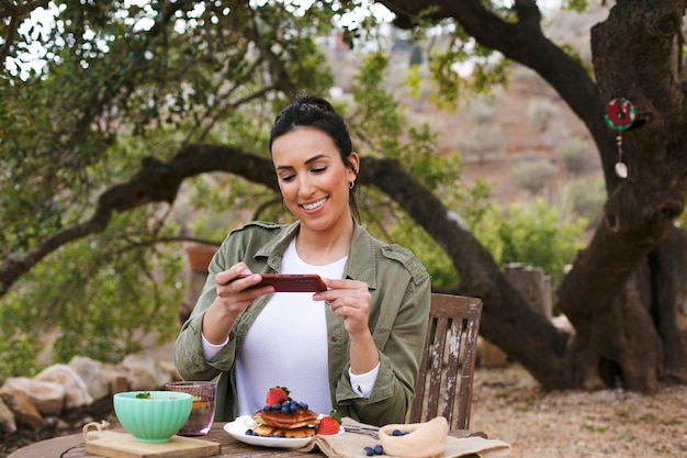 Foto gratuita mujer sonriente de tiro medio tomando fotos de comida