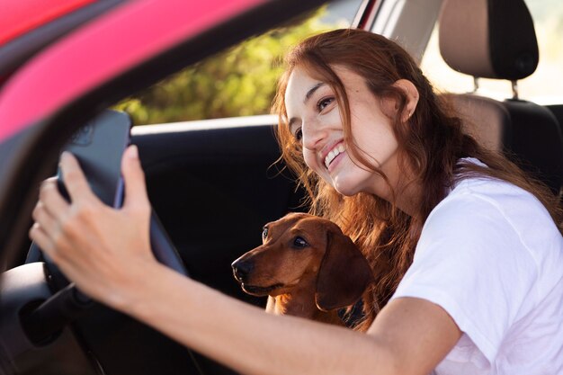 Mujer sonriente de tiro medio tomando selfie con perro