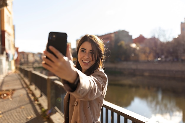 Mujer sonriente de tiro medio tomando selfie