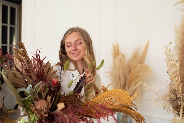 Mujer sonriente de tiro medio trabajando con flores secas