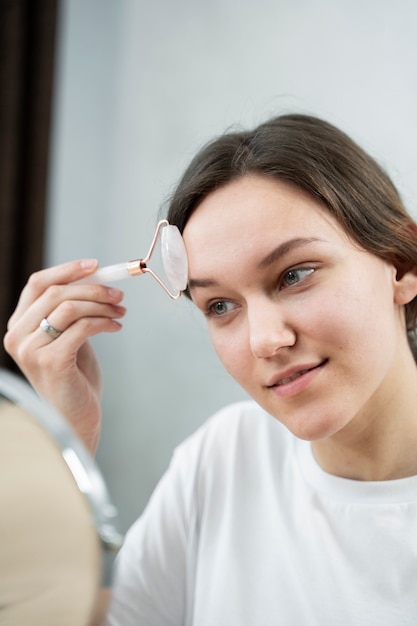 Mujer sonriente de tiro medio usando la herramienta de cara