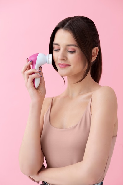 Mujer sonriente de tiro medio usando la herramienta de cara