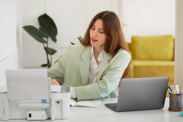 Mujer sonriente de tiro medio usando impresora en el trabajo