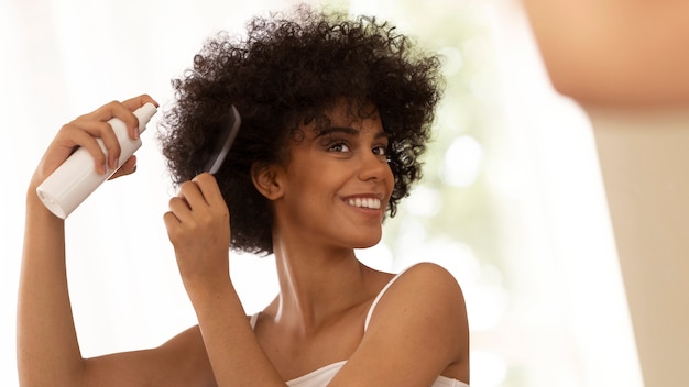 Mujer sonriente de tiro medio usando productos para el cabello