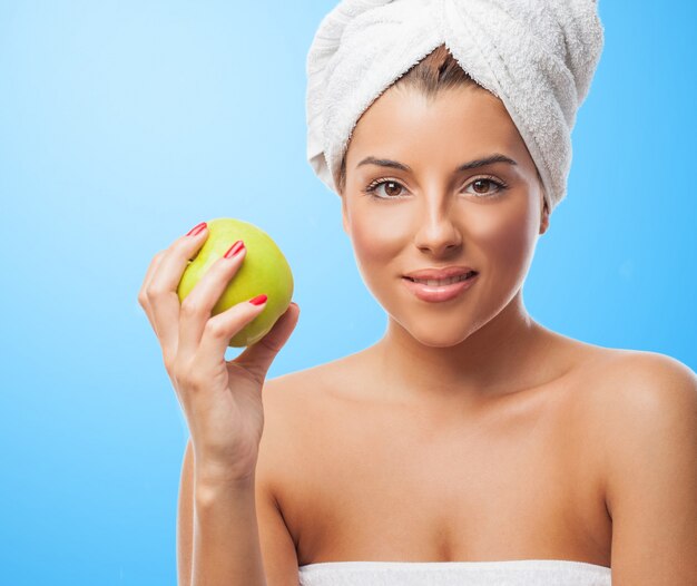 Mujer sonriente en una toalla blanca con la manzana