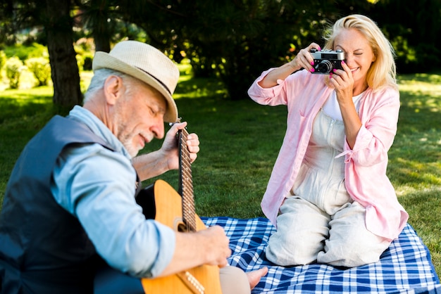 Mujer sonriente tomando una foto a un hombre con una guitarra