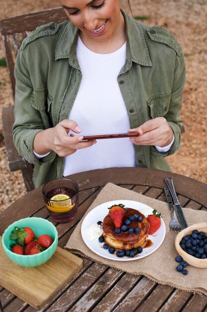 Mujer sonriente tomando fotos de comida