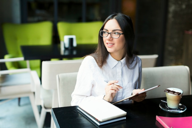 Mujer sonriente tomando notas en café