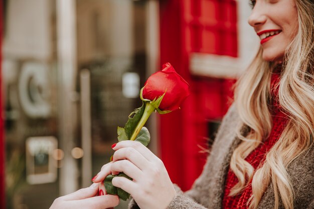 Mujer sonriente tomando rosa roja del hombre