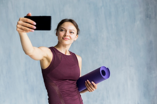 Foto gratuita mujer sonriente tomando una selfie mientras entrena